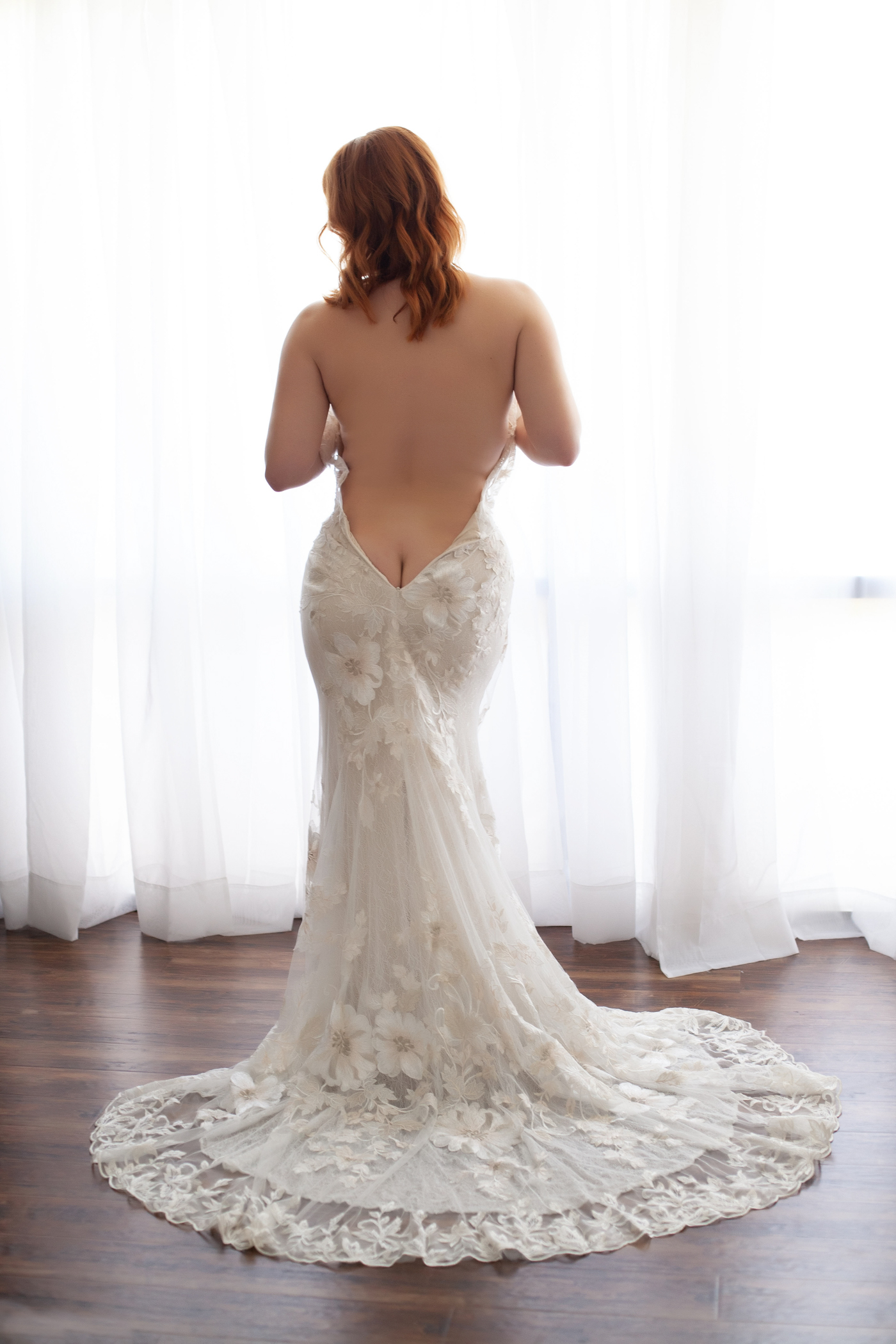 back of woman in low back wedding dress at a boudoir photoshoot
