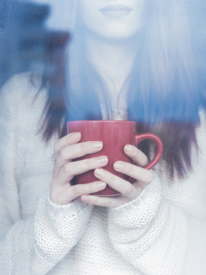 women with cozy white sweater holding a red coffee mug
