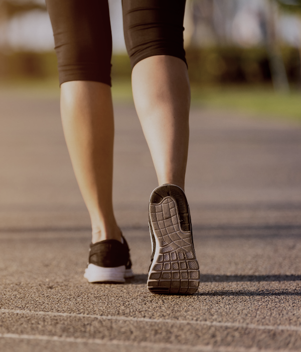 Image of woman's legs in tennis shoes walking along a road