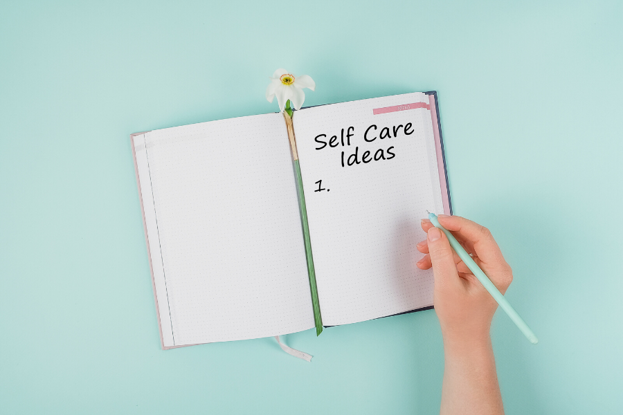 image of notebook open with a hand writing in it saying "self-care ideas"