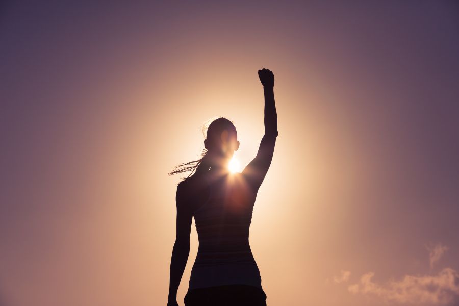 self-confidence - silhouette of woman holding fist into the air